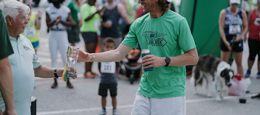A runner receiving an awards glass and medal at a race