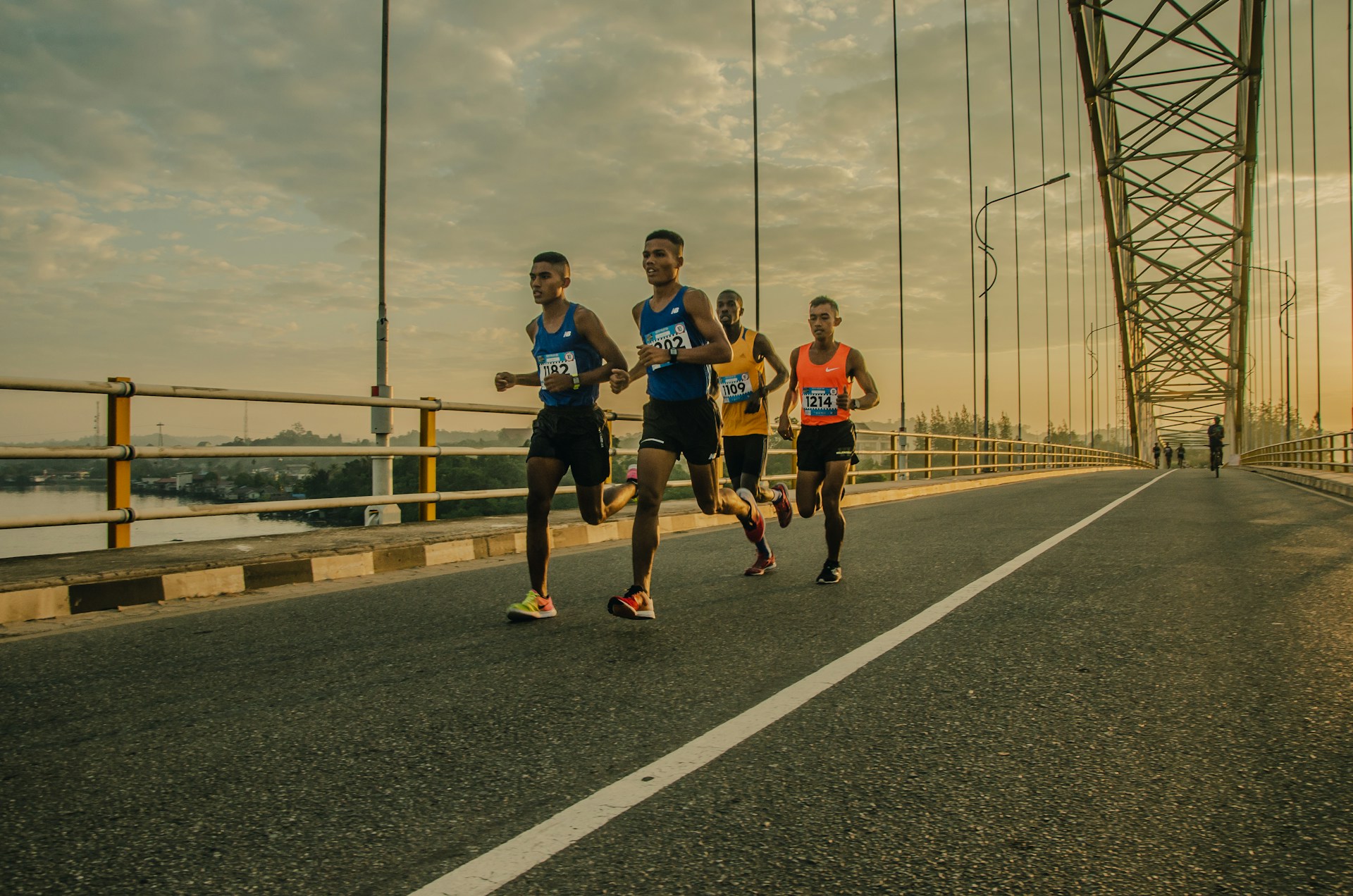 Group of marathon runners crossing a bridge at sunrise during a warm-weather race